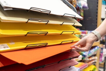 Customer's hand delicately selects a radiant orange sheet from a tiered display of colorful art...