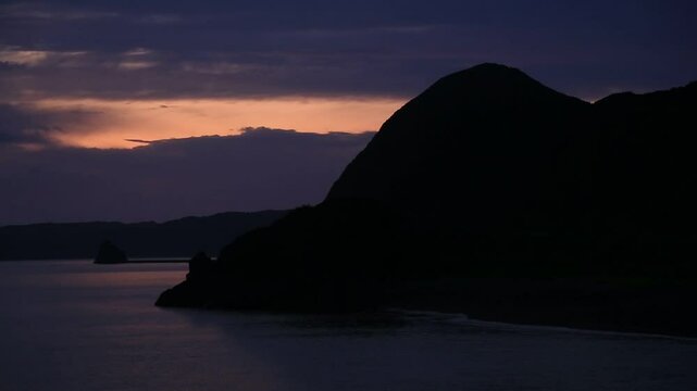 奄美大島の夏のの日の出前の島影と海。