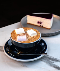 Cinnamon Latte with Marshmallows and Slice of Blueberry Cheesecake on Marble Table