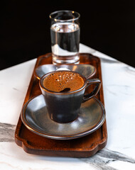 Authentic Turkish Coffee Served in Ceramic Cup with Glass of Water and Traditional Lokum on Wooden Tray