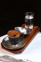 Authentic Turkish Coffee Served in Ceramic Cup with Glass of Water and Traditional Lokum on Wooden Tray
