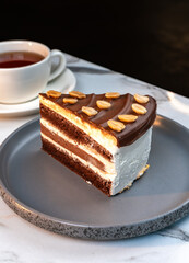 Layered Chocolate Cream Cake with Peanuts Served beside Cup of Hot Tea