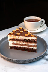 Layered Chocolate Cream Cake with Peanuts Served beside Cup of Hot Tea