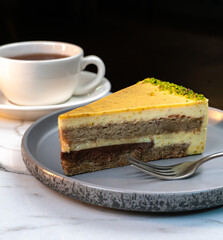 Lemon Pistachio Cake Slice with Tea in White Cup and Blurred Background