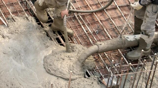 Construction workers pouring concrete on metal grid