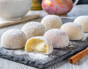 Fototapeta premium An array of Japanese mochi dusted with flour, highlighting its soft texture and creamy filling, set in a traditional cooking environment