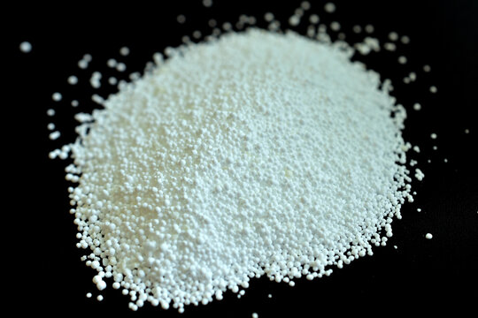 Granules of oxygen-saturated washing powder lie in a heap on a black background.