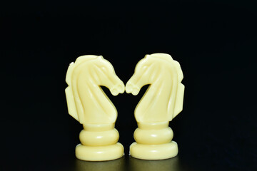 Chess pieces two knights, white on a black background.
