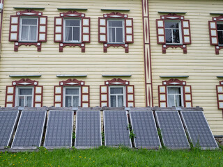 Modern solar panels for electricity generation near the wall of a renovated old Karelian house in...