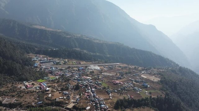 Aerial view of Lukla Airport in the Himalayas of Nepal, showcasing traditional architecture and a majestic mountain valley