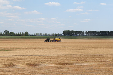 a farmer is threshing flax with machinery at a field in the dutch countryside in summer