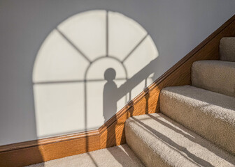 Rounded window lighting a carpeted stairs and railing on a white wall