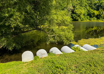 Large corrugated pipes draining into a retention pond in summer