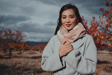 Young beautiful asian woman posing in autumn valley with red trees