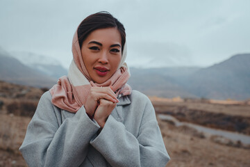 Young beautiful asian woman portrait on mountains background on cold autumn day