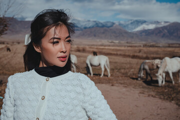 Young beautiful asian woman posing with horses in the mountains