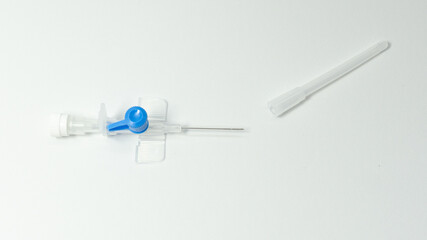 Intravenous cannula with fully exposed needle and detached protective cap. Sterile medical device ready for venous access, placed on white background.