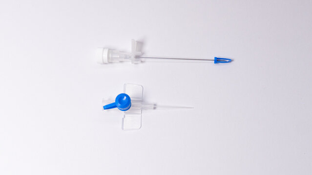 IV cannula and its needle separated after use. Blue injection port and protective needle cap displayed on white background.