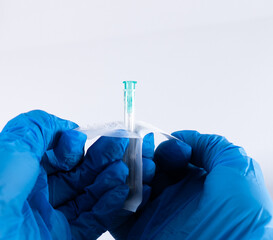 Gloved hands opening a sterile needle from its blister packaging. The needle is still inside the...
