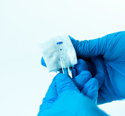 Gloved hands holding a sealed glass ampoule with a gauze pad placed on its neck. Sterile...