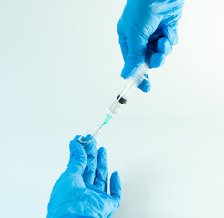 Close-up of gloved hands drawing fluid from a medicine vial using a syringe. Clinical setting ideal...