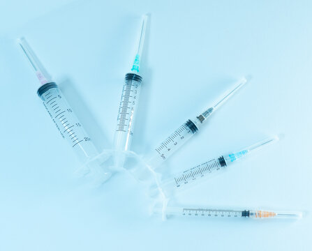 A set of sterile medical syringes on a white surface. Each syringe has a different colored needle cap, representing various sizes or types of medical use. 