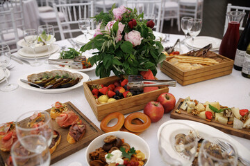 Elegant table setting with a variety of appetizers, fresh fruit, and a lush floral centerpiece. Dishes include assorted cheese, meats, and pastries, creating a festive atmosphere.