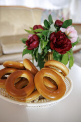 Freshly baked bagels rest in a basket next to a vibrant floral arrangement. The combination of delicious bread and colorful flowers creates a warm and inviting atmosphere.