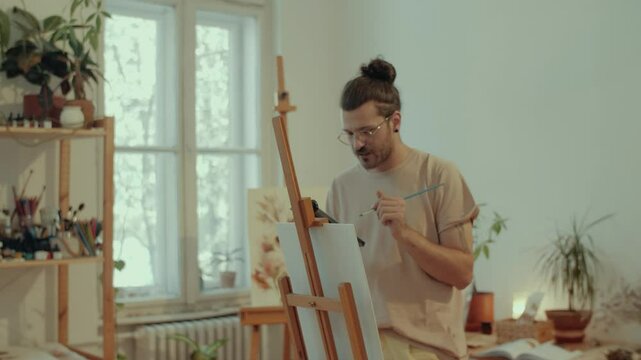 Talented artist painting on canvas, using phone as reference