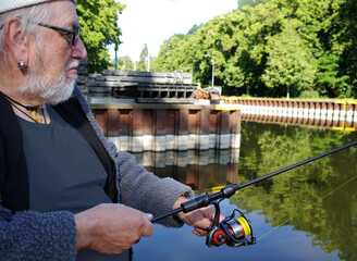 An elderly man passes the time fishing while waiting for the lock to open. The lock is visible in the background
