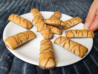 Fresh chocolate covered cookies on a plate,woman holding a cookie,pastry,home cooking.