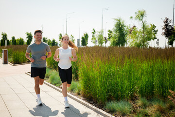 Joyful joggers embrace the sunny day in a vibrant urban park, sharing smiles and positivity during...