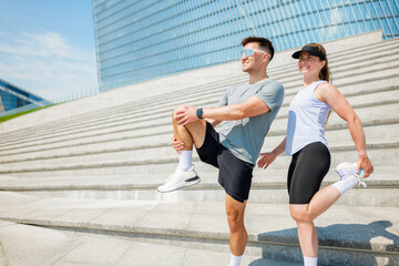 Joyful fitness enthusiasts stretching on modern steps in a vibrant urban setting under bright...