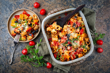 Homemade Italian baked cheesy mezze maniche pasta alla norma with eggplant, olives and tomatos served as top view in a stoneware casserole