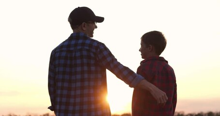 father and son silhouette at sunset shows father s loving embrace and strong bond outdoors. father shares warmth and care with son, capturing emotional connection during peaceful family moment.
