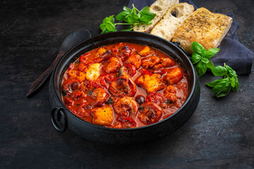 Traditional artisan homemade gambas prawn und fish stew romesco de peix served as close-up in cast-iron skillet