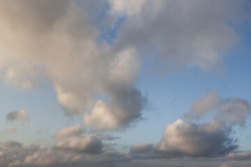 Clouds drift across a clear blue sky at sunset, casting soft shadows and creating a serene...
