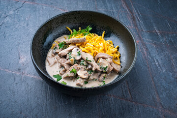 Traditional Swiss Zürcher geschnetzeltes from veal with mushrooms spaetzle in cream sauce served as close-up in a design bowl