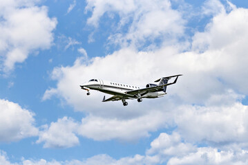 Private business plane flying under a blue sky with white clouds	