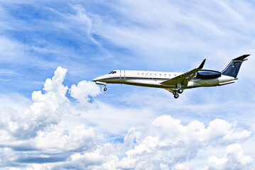 Private business plane flying under a blue sky with white clouds	