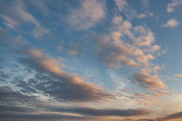 Beautiful clouds in a vibrant sunset sky over the horizon near a tranquil body of water during late afternoon