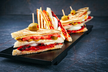 Traditional club toast sandwich with ham, cheese and egg served with vegetables as close-up on a wooden design board