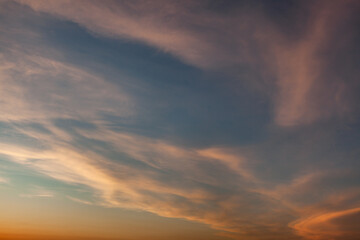Dramatic sunset clouds illuminate the sky over a tranquil landscape in the evening