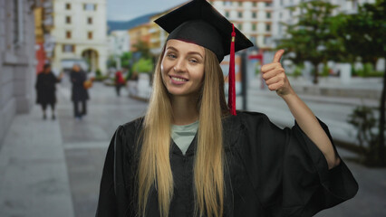 Woman in graduation uniform standing on city street showing thumbs up and thumbs down with...