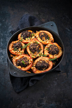 Traditional half quince stuffed with minced lamb meat, herbs and pine nuts served as close-up in cast iron skillet