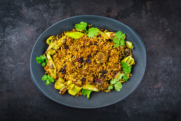 Traditional Indian biryani tikka masala chicken curry and Biryani with chili and raisins served as close-up on a design plate