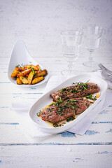 Juicy Easter lamb fillet roasted in butter with herbs and crunchy potato wedges served as close-up...