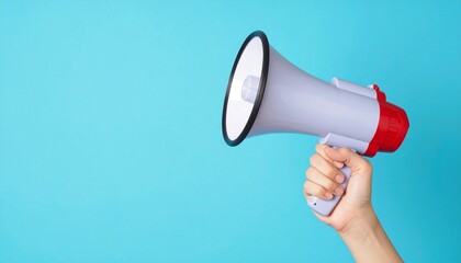 Hand Holding Gray Megaphone Against Solid Blue Background for Communication and Announcements
