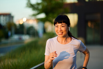 Portrait of a young beautiful sport woman smiling happy and confident. Running   in city park...