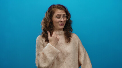 Woman making disgusted facial expression against isolated blue background wearing cozy sweater...
